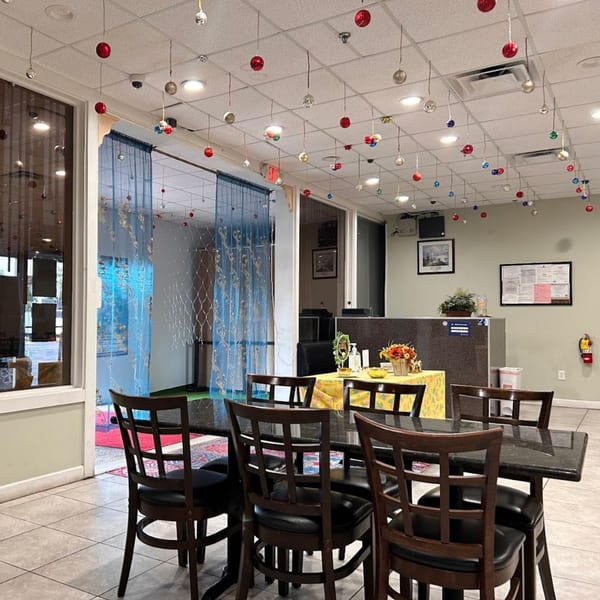 Interior of Bombay Curry dining area with tables, chairs, and festive ornaments hanging from the ceiling.