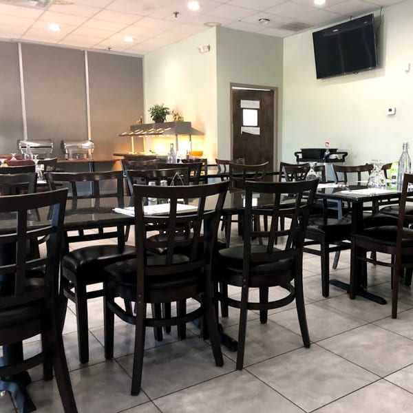 Interior of Bombay Curry restaurant with empty tables, chairs, and a buffet line.